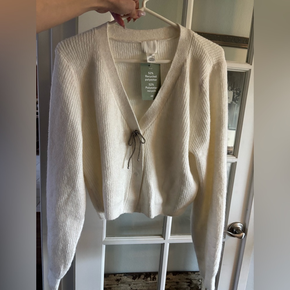 H&M cream sweater w two metal buttons and the top button has a jeweled bow.